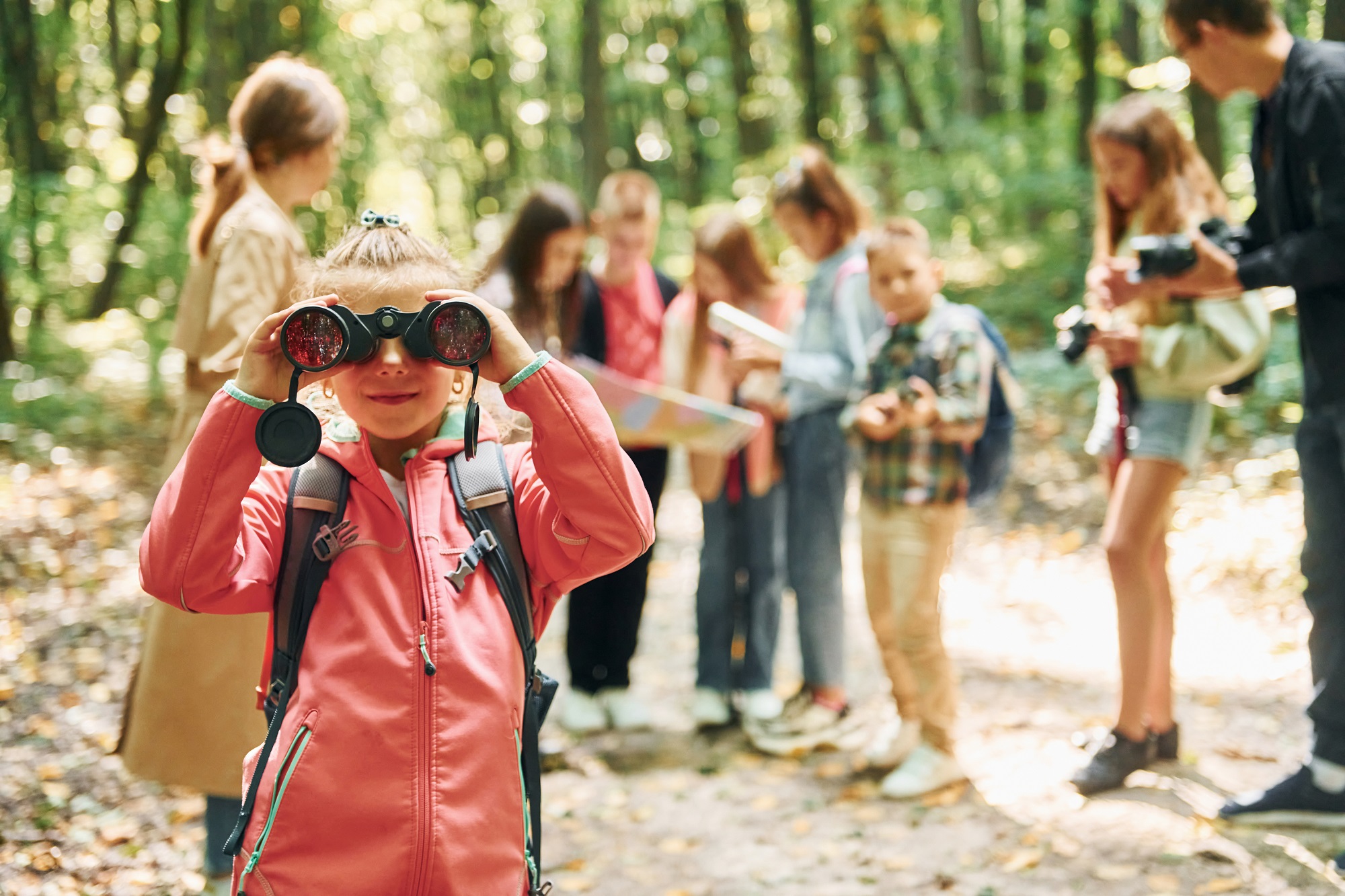 girl-looking-into-binoculars-kids-green-forest-summer-daytime-together